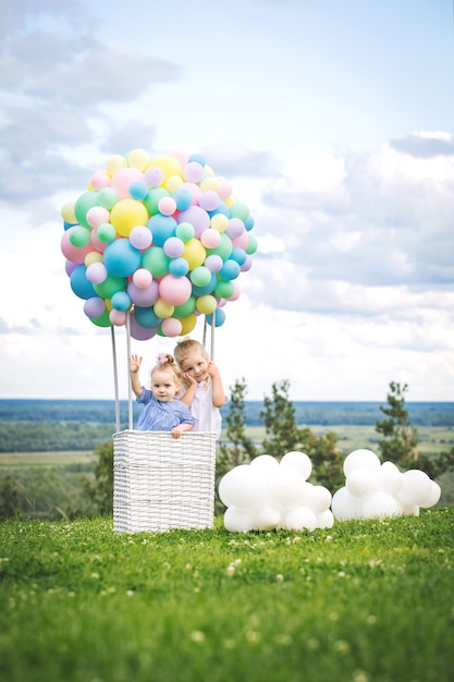 Kleine süße Mädchenkinder schön und glücklich mit Ballonluftschiff auf blauem Himmelshintergrund mit Wolken