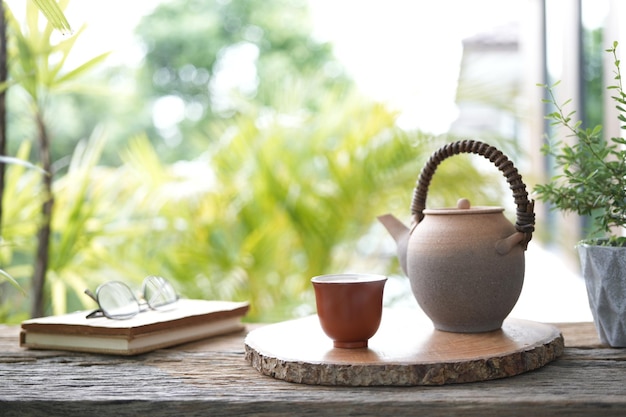 kleine Teetasse und alte Kanne auf Holztisch mit Notizbuch und Gläsern