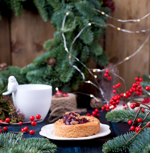 kleine Torte mit Preiselbeeren Marmelade auf einem blauen hölzernen Weihnachtsbaum
