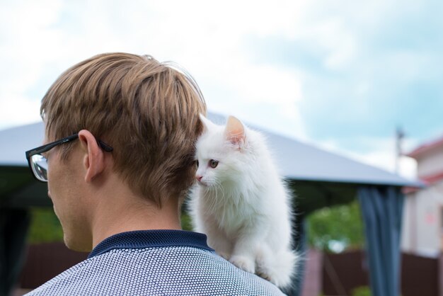 kleine weiße Katze auf den Schultern eines Mannes