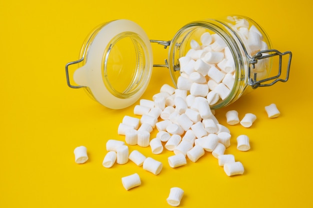 Kleine weiße Marshmallows für Dekoration und Getränke und Dekoration von Kuchen in einem Glas auf gelbem Hintergrundkopierraum