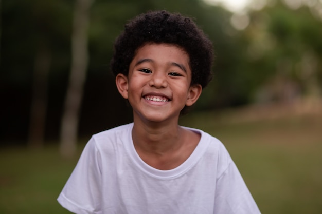 Foto kleiner afrojunge, der im park in die kamera lächelt