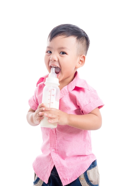Kleiner asiatischer Junge, der das rosa Hemd hält die Milchflasche lächelt über weißem Hintergrund trägt