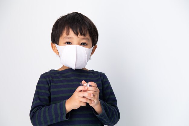 Kleiner asiatischer Junge mit Gesundheitsmaske schützen Virus auf Weiß