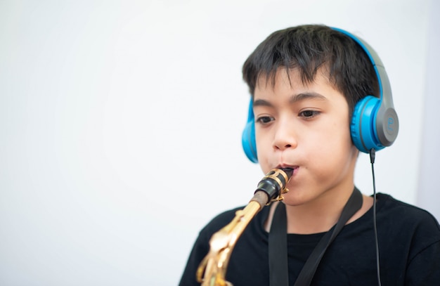 Kleiner asiatischer Junge studiert Saxophoninstrumentmusik online zu Hause