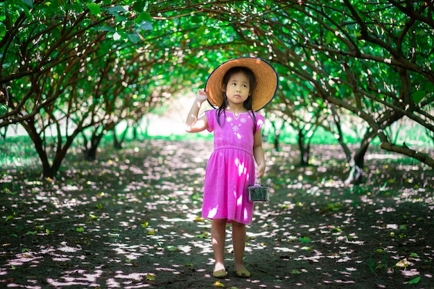 Kleiner asiatischer Mädchenabnutzungshut, der die Maulbeerfrucht im Garten schaut