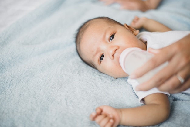 Kleiner asiatischer neugeborener Junge schläft und trinkt morgens Milch auf einem bequemen Bett