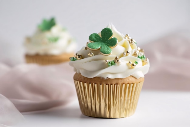 Kleiner Cupcake mit Sahne und Goldperlen und einem grünen Klee auf einem hellen Hintergrund Grünes vierblättriges Klee, Symbol des St. Patrick's Day