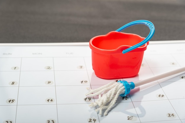 Kleiner Eimer und Mopp im Kalender Geplante Bereinigung Konzept der allgemeinen Frühjahrsreinigung