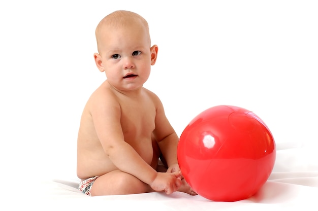 Kleiner einjähriger Junge spielen mit großem Spielzeugball auf einem isolierten weißen Hintergrund