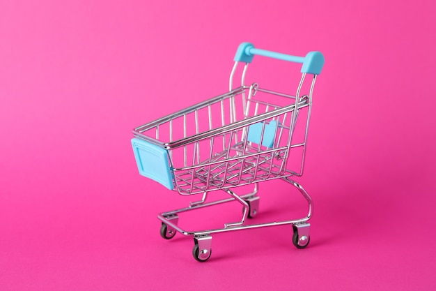 Kleiner Einkaufswagen auf rosa Raum, Platz für Text