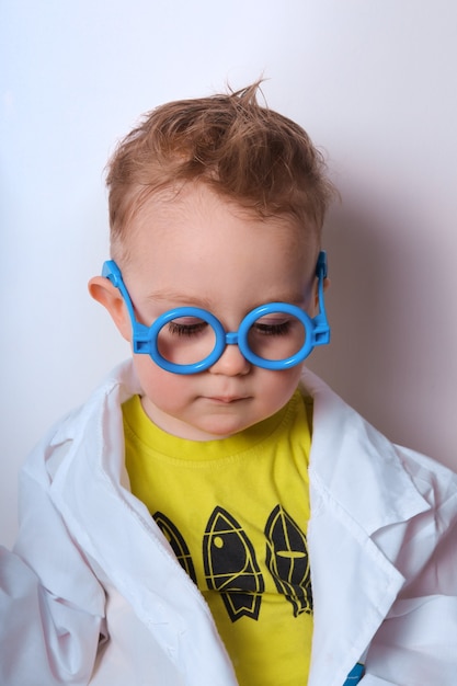 Kleiner Entdecker Junge spielt Wissenschaftler Lustiges Kind mit blauer Brille Nettes buntes Foto Doktor