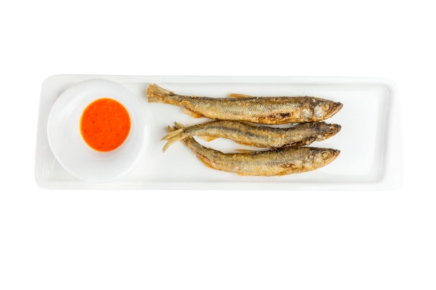 Kleiner gebratener Fisch mit Soße auf einem weißen Teller Traditioneller Snack für Bier Closeup Draufsicht isoliert auf weißem Hintergrund