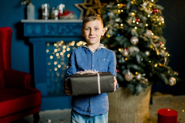 Kleiner glücklicher Junge hält Weihnachtsgeschenke