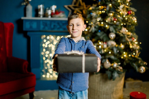 Kleiner glücklicher Junge hält Weihnachtsgeschenke