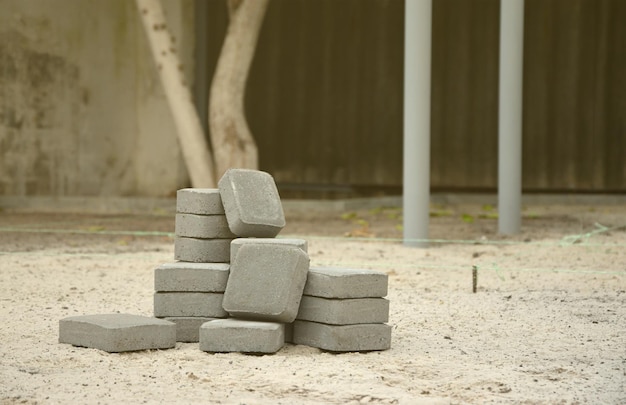 Kleiner Haufen grauer Gehwegplatten, die im Freien in Stapel gelegt werden, Material für die Verlegung von Platten durch Mosaik in