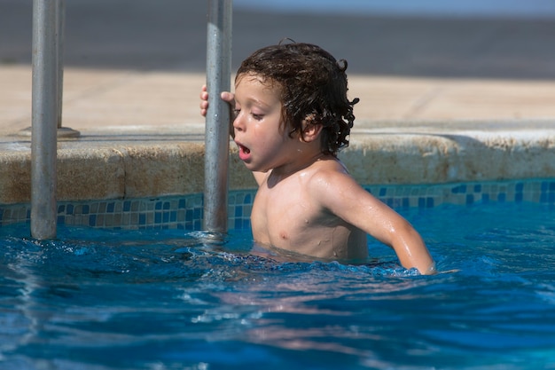 Kleiner Junge 45 Jahre alt, der Spaß im Pool im Wasser hat und anfängt zu schwimmen