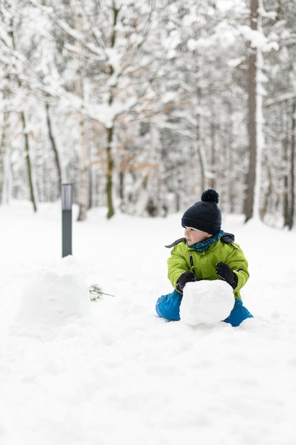 Foto kleiner junge amüsiert sich beim spielen im schnee