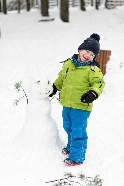 Foto kleiner junge amüsiert sich beim spielen im schnee