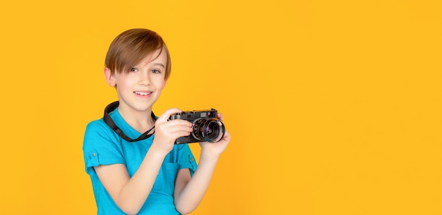 Kleiner Junge auf einem Foto mit einer Vintage-Kamera. Kind im Studio mit professioneller Kamera. Junge mit einer Kamera