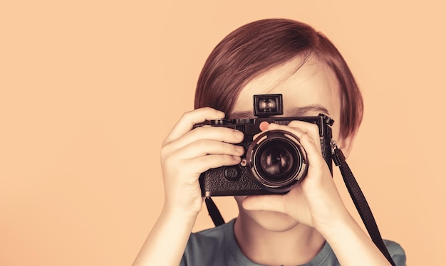 Kleiner Junge auf einem Fotografieren mit einer Vintage-Kamera Kind im Studio mit professioneller Kamera Junge mit einer Kamera Baby Junge mit Kamera Fröhlich lächelndes Kind, das eine Kamera hält