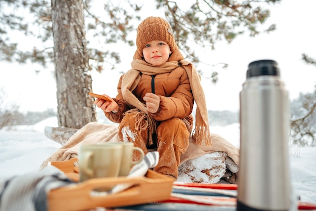 Kleiner Junge auf einem Picknick im Winterwald