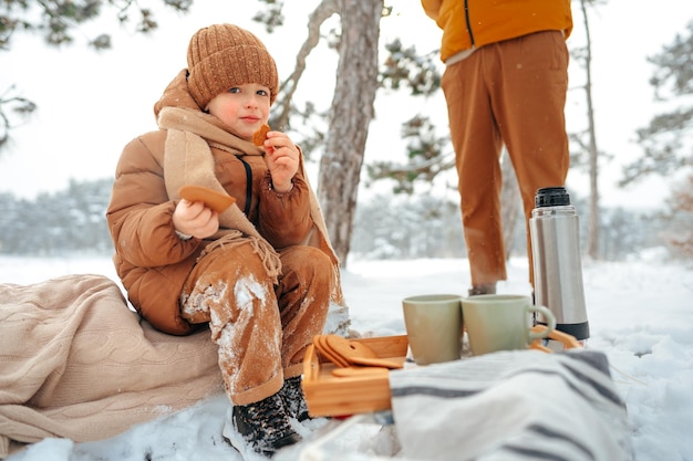 Kleiner Junge auf einem Picknick im Winterwald