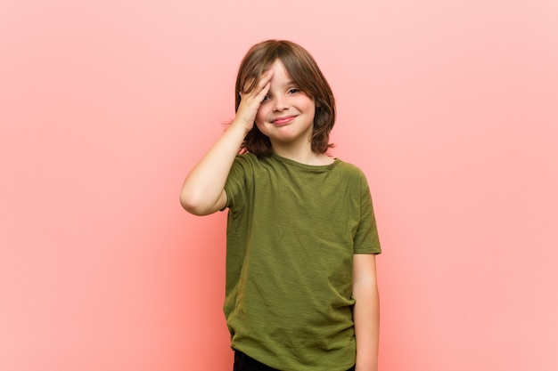 Kleiner Junge blinzelt mit den Fingern in die Kamera, verlegenes Deckgesicht.