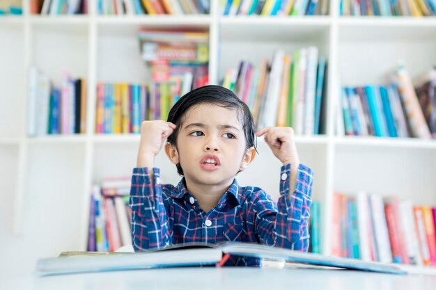 Kleiner Junge denkt etwas in der Bibliothek nach