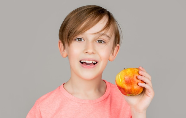 Kleiner Junge, der Apfel isst. Junge Äpfel zeigen. Kind mit Äpfeln. Porträt des netten kleinen Kindes, das einen Apfel hält