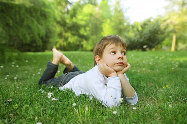 Kleiner Junge, der auf dem Gras liegt