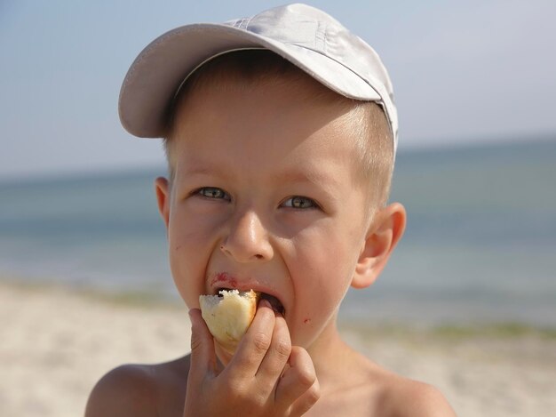 Kleiner Junge, der Brötchen auf dem Meer isst