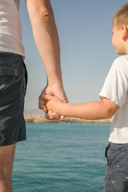 Kleiner Junge, der die Hand seines Vaters hält