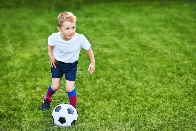 Kleiner Junge, der draußen Fußball übt