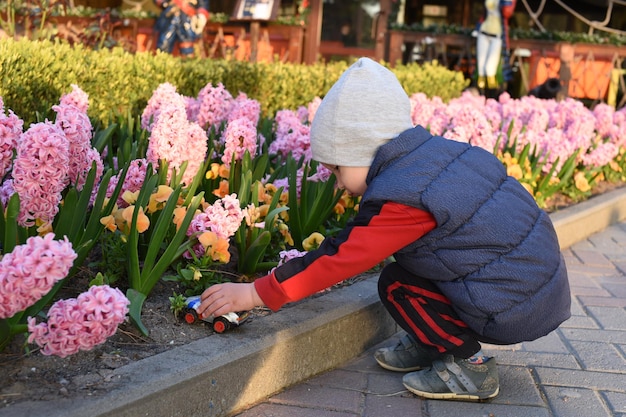 Kleiner Junge, der draußen im Garten Spielzeugauto spielt