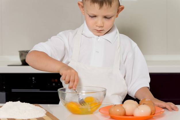 Kleiner Junge, der Eier in einer Schüssel mischt