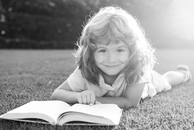 Kleiner Junge, der ein Buch im Sommersonnenunterganglicht liest