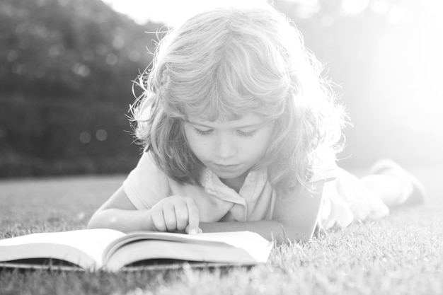 Kleiner Junge, der ein Buch im Sommersonnenunterganglicht liest