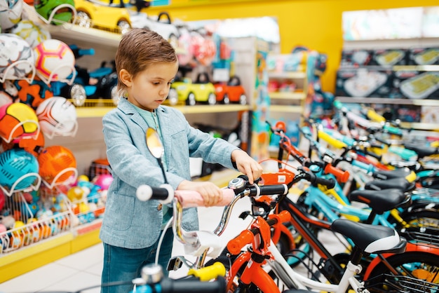 Kleiner Junge, der Fahrrad im Kindergeschäft kauft