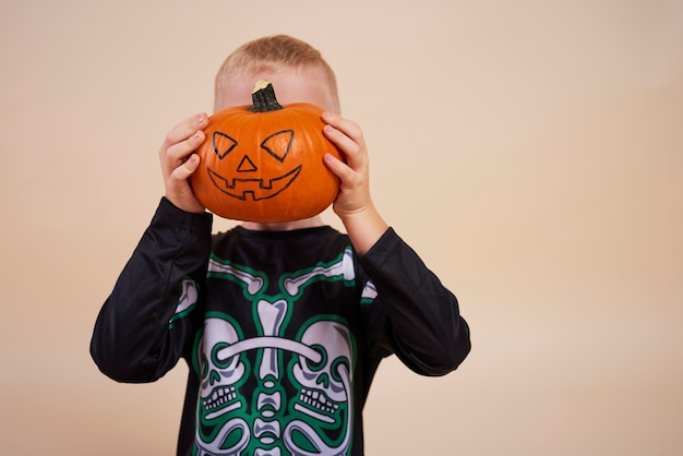 Kleiner Junge, der Halloween-Kürbis vor seinem Gesicht hält