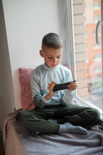 Kleiner Junge, der Handyspiel auf dem Smartphone spielt, sitzt auf einem Sofa, Draufsicht Kinderfreizeit zu Hause Video