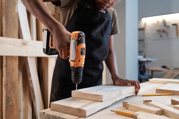 Kleiner Junge, der Holz bohrt