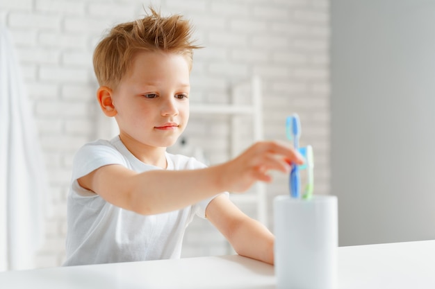 Kleiner Junge, der im Badezimmer nach Zahnbürste greift