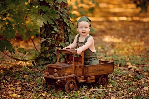 Kleiner Junge, der im hölzernen Kinderspielzeugauto sitzt