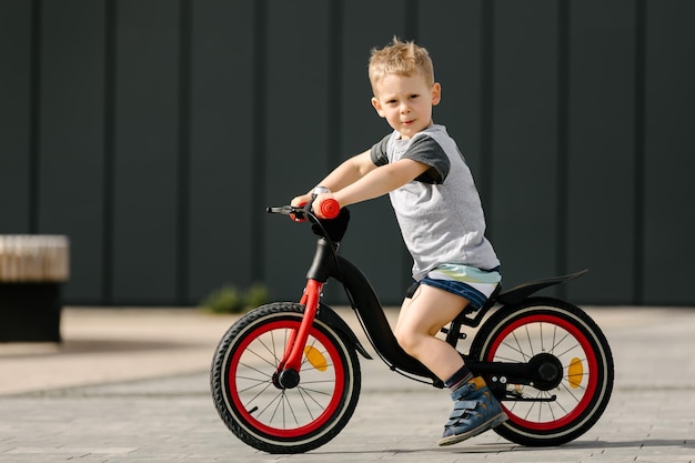 Kleiner Junge, der in einem Stadtpark Fahrrad fährt