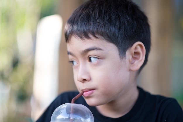 Kleiner Junge, der kaltes Mischmilch-alkoholfreies Getränk trinkt, indem er Stroh verwendet