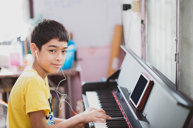 Kleiner Junge, der Klavier digitales digitales Tablett zu Hause übt