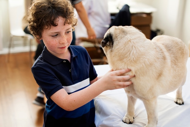 Foto kleiner junge, der mit einem pug spielt