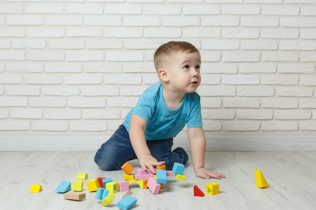 Foto kleiner junge, der mit erbauer auf weißem hintergrund spielt. baby, das blockspielwaren spielt