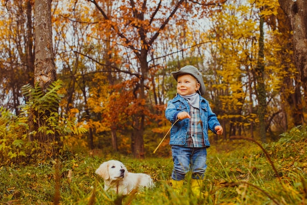 kleiner Junge, der mit Golden Retriever-Welpen im Park spazieren geht